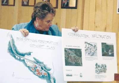 Ruidoso Village Manager Debi Lee holds up placards that decribe various aspects of the Bog Springs project planned at Ruidoso High School. (Dianne Stallings/Ruidoso News)